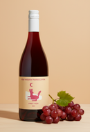 Wine bottle with a label and a bunch of grapes on a beige background