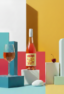 Bottle of Cherry wine with a glass on a colorful geometric background