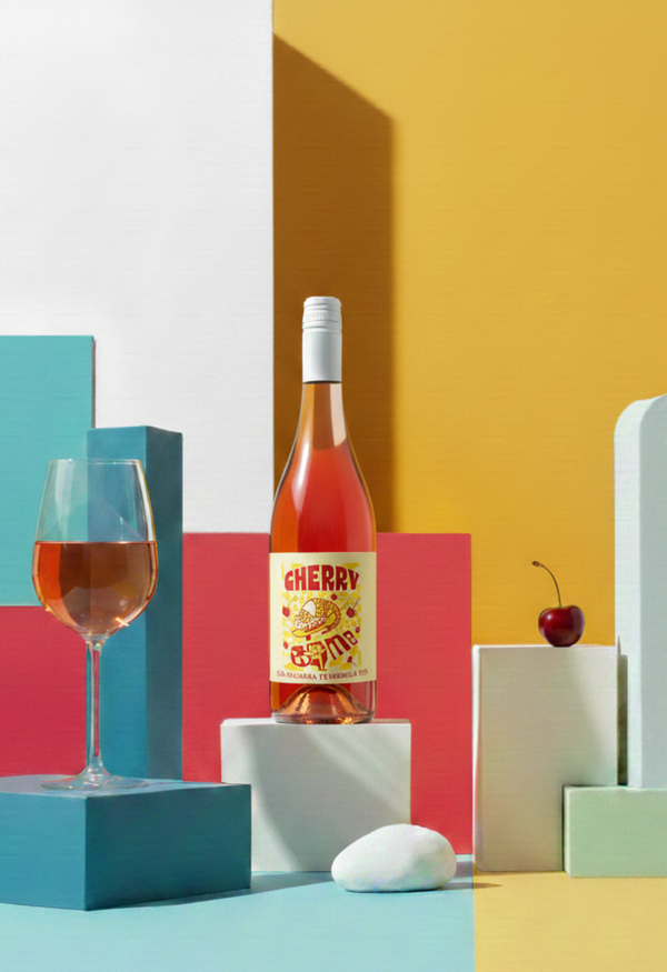 Bottle of Cherry wine with a glass on a colorful geometric background