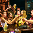 Happy group of friends in a bar, with green meanie on the bar