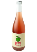 A bottle shot of Pomme Pomme Pomme. the bottle is clear with a silver crown cap, and a rosy hazy wine.  The label is a cream band with a drawing of a green apple and the words Pomme Pomme Pomme below the apple descending to the bottom of the label