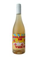 "A bottle of Holiday in the Sun wine with a pale yellow hue. The label features bold red text 'Holiday in the Sun' on a vibrant yellow background with sun rays, palm trees, and a white convertible car illustration with a figure reclining inside. The design evokes a tropical, summer vibe."