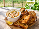 Whipped feta with hot honey, thyme, and paprika oil served with charred sourdough and a glass of Traynor white wine at the vineyard in Hillier, Prince Edward County